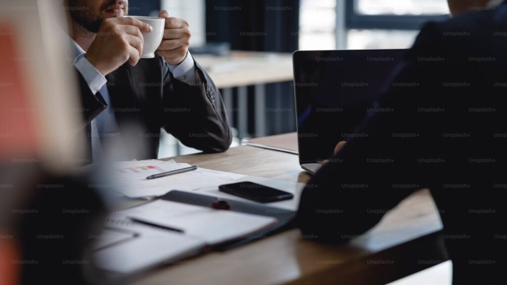 ーヒーを片手に、デスクで真剣な対話をする二人の人物