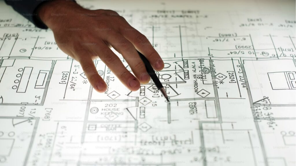 デスク上の戦略的な設計図を指し示す手